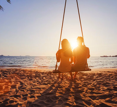 couple on a swing by the beach